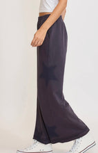 Person wearing dark wide-leg pants with a white background