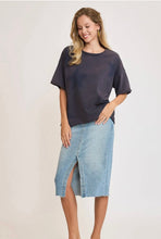 Woman wearing a dark navy oversized sweatshirt short sleeves with stars on a plain background in a skirt