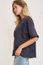 Woman wearing a dark navy oversized sweatshirt short sleeves with stars on a plain background