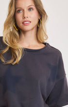 Woman wearing a dark navy oversized sweatshirt short sleeves with stars on a plain background
