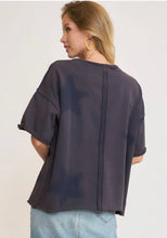 Woman wearing a dark navy oversized sweatshirt short sleeves with stars on a plain background