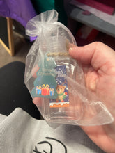 Hand holding an organza bag with clear plastic bottle containing hand sanitizer with a Christmas-themed label