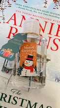 Hand holding an organza bag with clear plastic bottle containing hand sanitizer with a Christmas-themed label