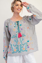Woman wearing a colorful embroidered blouse with a plain background
