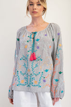 woman wearing black striped top with colorful embroidery white background