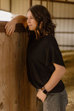 Woman leaning against a wooden wall inside a barn