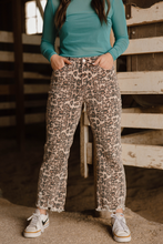 Person wearing leopard print pants and a teal top in an indoor setting.