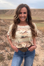 Woman wearing a patterned top and jeans standing in a desert landscape