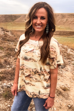 Woman wearing a desert-themed shirt standing in a natural landscape