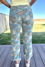 Person wearing blue jeans with horse and fish pattern outdoors