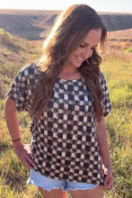 Woman wearing a checkered top and denim shorts in a grassy field