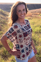 Woman wearing a colorful patterned shirt in a grassy field