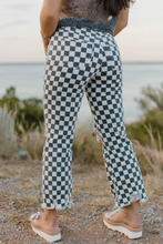 Person wearing checkered pants standing outdoors with a scenic background